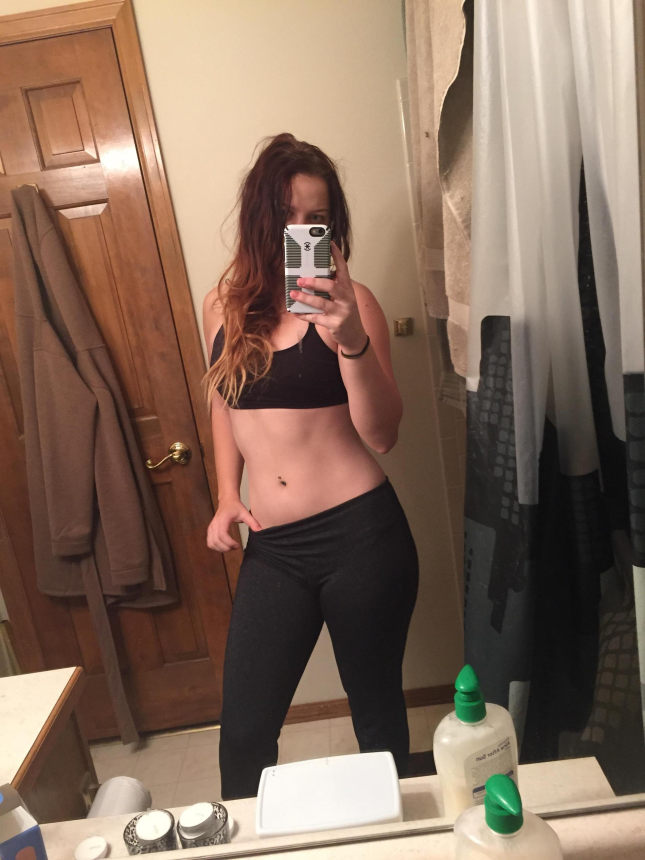 Фото Девушка стоит перед зеркалом, наслаждаясь своей фигурой и делая селфи